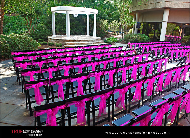 outdoor wedding ceremony complete with pink bows on back of the chairs
